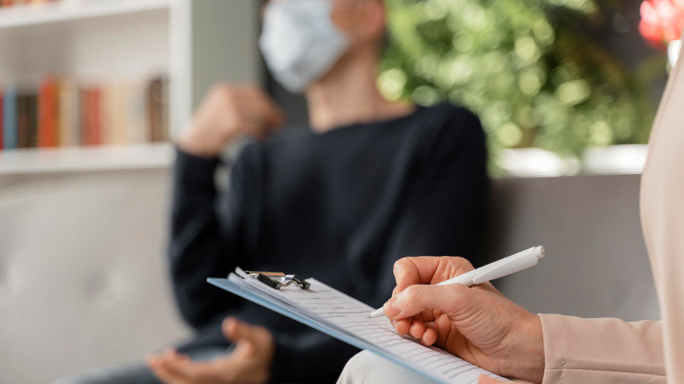 https://www.therapmed.ch/wp-content/uploads/2021/11/woman-therapist-taking-notes-of-man-in-therapy-office-with-mask.jpg